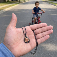 Thumbnail for The black teardrop photo pendant in an open palm, real small size, a little boy riding his bike behind | SKU: TPH-DRPN-BLACK