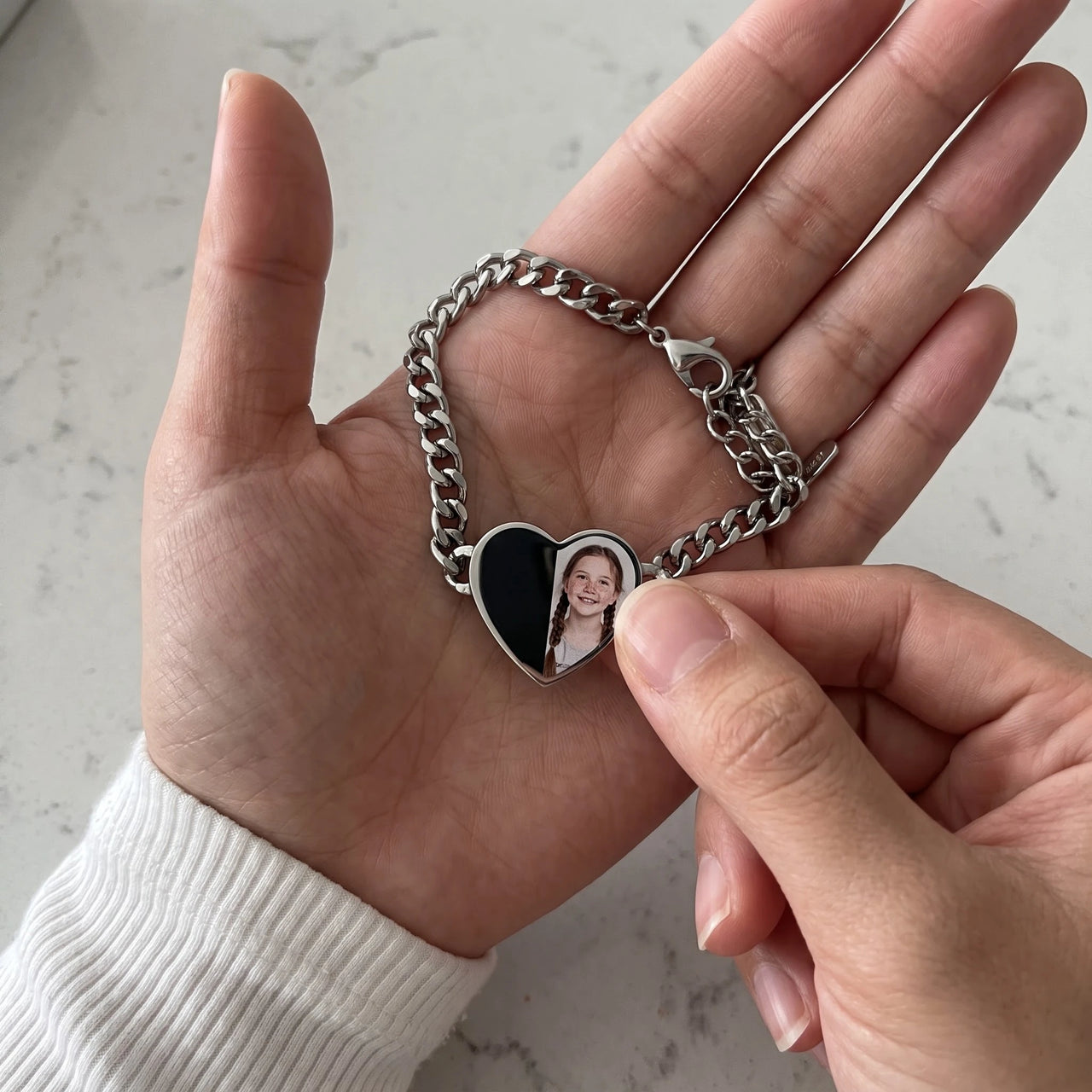 Thumb warming the silver heart bracelet plate: the hidden photo appears under the thumb while the rest stays black | SKU: TPH-HRTB-SILVER