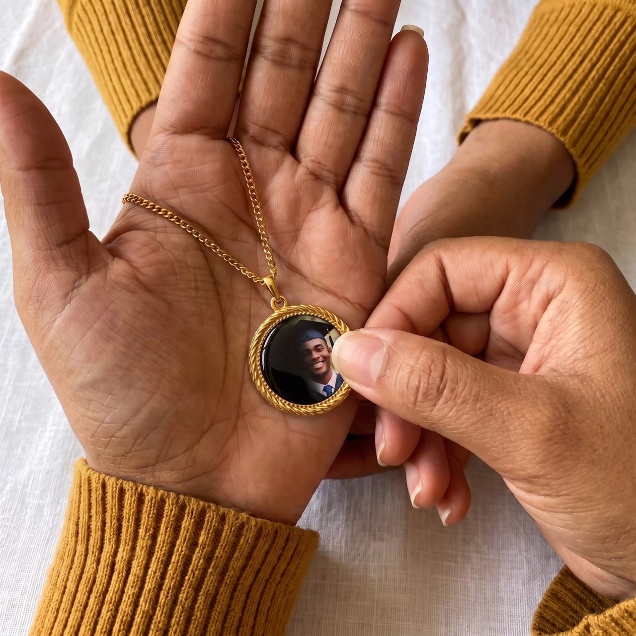 Thumb warming the gold round pendant: the hidden photo appears under the thumb while the rest stays black | SKU: TPH-RNDN-GOLD